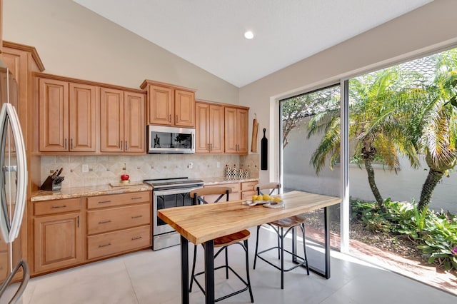 6690 Remington Pl, Lake Worth, FL 33463 - kitchen featuring stainless steel appliances, decorative backsplash, plenty of natural light, vaulted ceiling, and light stone counters