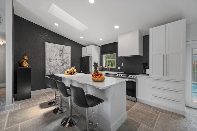 14244 Horseshoe Trce, Wellington, FL 33414 - kitchen with stainless steel appliances, a kitchen island, a skylight, vaulted ceiling, and white cabinets