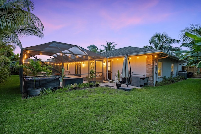 14244 Horseshoe Trce, Wellington, FL 33414 - back of property at dusk with a yard, a patio area, glass enclosure, and stucco siding