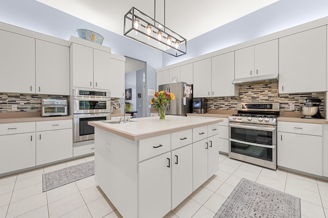 756 SW Pelican Cv, Port Saint Lucie, FL 34986 - kitchen with stainless steel appliances, under cabinet range hood, light countertops, backsplash, and light tile patterned floors