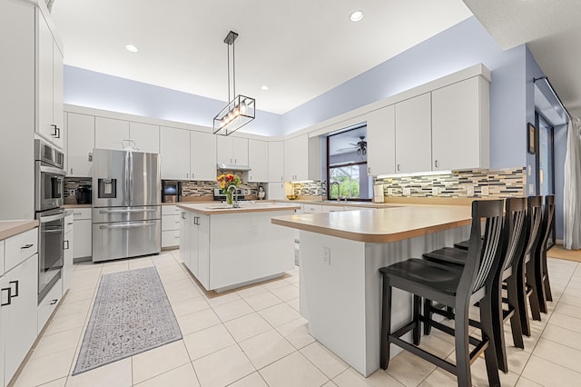 756 SW Pelican Cv, Port Saint Lucie, FL 34986 - kitchen with stainless steel appliances, decorative backsplash, a peninsula, decorative light fixtures, and recessed lighting