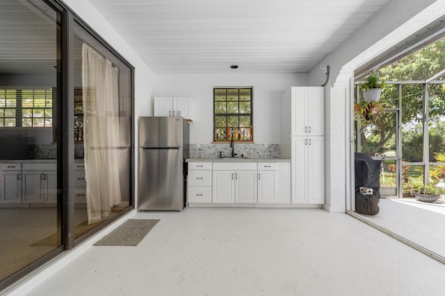 756 SW Pelican Cv, Port Saint Lucie, FL 34986 - kitchen with freestanding refrigerator, light countertops, white cabinetry, light flooring, and decorative backsplash