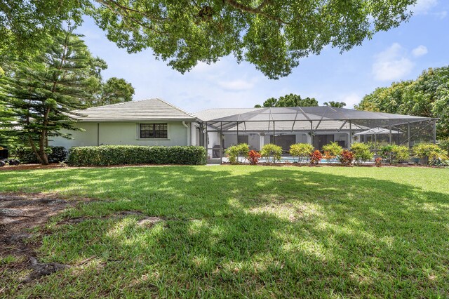 756 SW Pelican Cv, Port Saint Lucie, FL 34986 - rear view of house with a lawn, a tiled roof, stucco siding, and glass enclosure