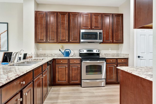 5030 Dulce Ct, Palm Beach Gardens, FL 33418 - kitchen with stainless steel appliances, a sink, light wood-style flooring, and light stone countertops