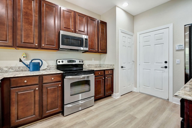 5030 Dulce Ct, Palm Beach Gardens, FL 33418 - kitchen featuring stainless steel appliances, light wood-style floors, baseboards, and light stone countertops