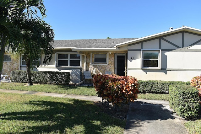 2597 Emory Dr W Unit G, West Palm Beach, FL 33415 - ranch-style house featuring stone siding, a front lawn, roof with shingles, and stucco siding