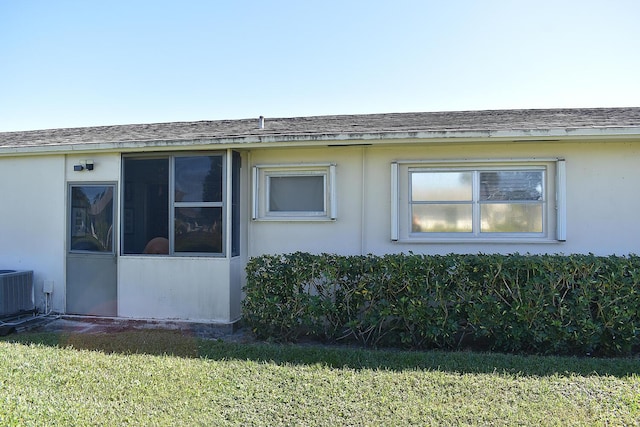 2597 Emory Dr W Unit G, West Palm Beach, FL 33415 - view of property exterior with a lawn, central AC unit, and a shingled roof