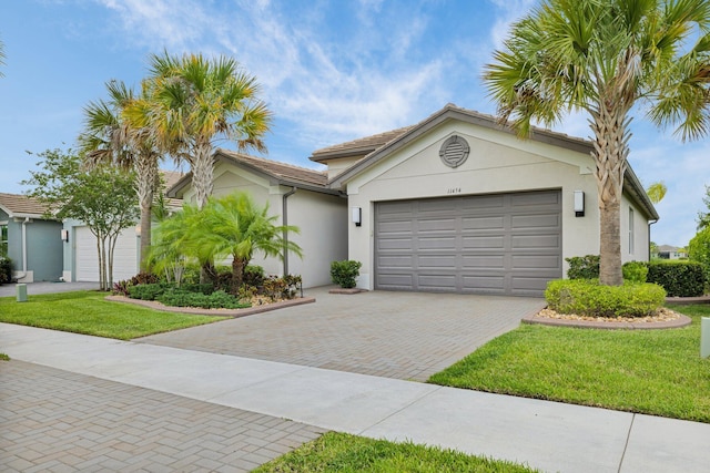 11454 SW Hawkins Ter, Port Saint Lucie, FL 34987 - view of front of house featuring stucco siding, a garage, decorative driveway, and a front yard