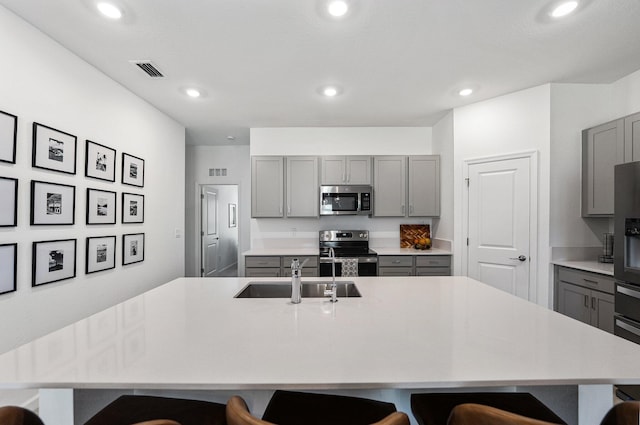 956 Bent Creek Dr, Fort Pierce, FL 34947 - kitchen with appliances with stainless steel finishes, gray cabinets, a sink, a breakfast bar area, and recessed lighting