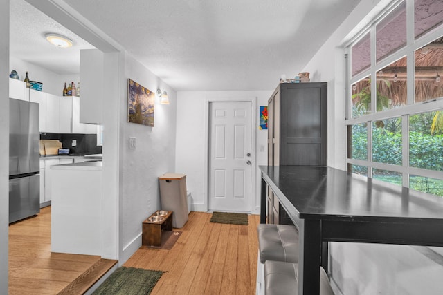 1005 SW 15th Ter, Fort Lauderdale, FL 33312 - kitchen with freestanding refrigerator, white cabinetry, a textured ceiling, baseboards, and light wood finished floors