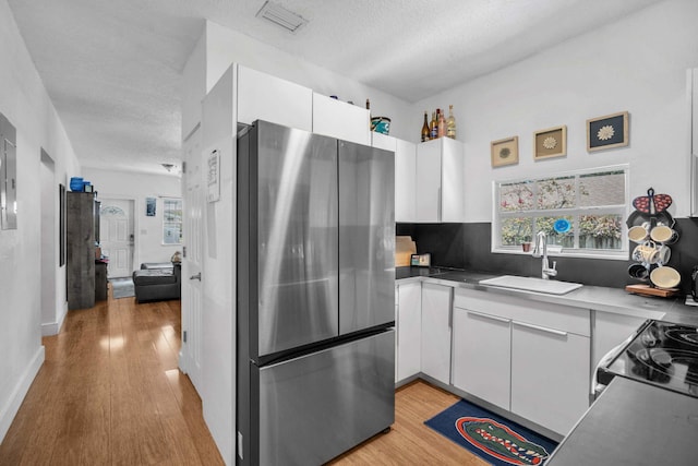 1005 SW 15th Ter, Fort Lauderdale, FL 33312 - kitchen with freestanding refrigerator, a sink, white cabinets, a textured ceiling, and light wood-style floors