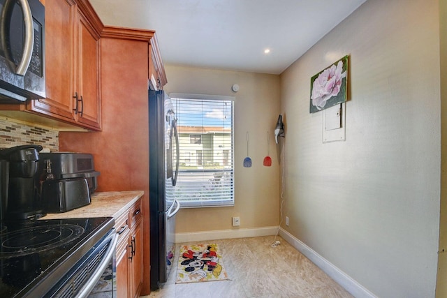 799 Hill Dr Unit F, West Palm Beach, FL 33415 - kitchen with appliances with stainless steel finishes, brown cabinetry, light countertops, baseboards, and backsplash