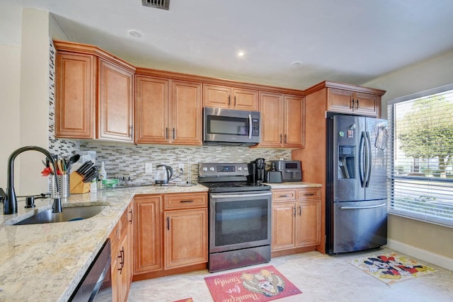 799 Hill Dr Unit F, West Palm Beach, FL 33415 - kitchen featuring stainless steel appliances, a sink, light stone counters, backsplash, and brown cabinetry
