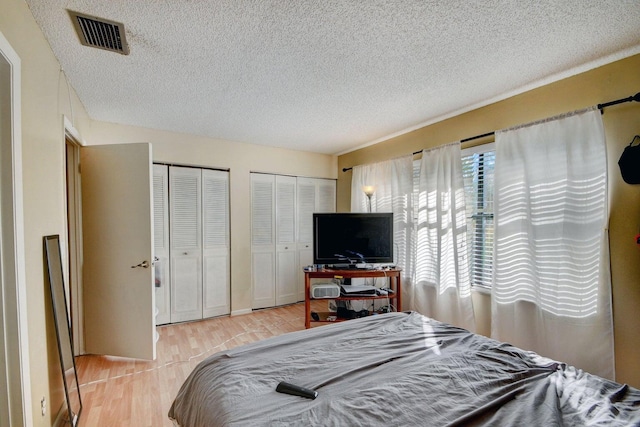 799 Hill Dr Unit F, West Palm Beach, FL 33415 - bedroom featuring two closets, a textured ceiling, and light wood-style floors