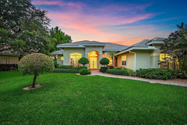 18974 SE Jupiter River Dr, Jupiter, FL 33458 - view of front facade featuring stucco siding, a front lawn, and a tiled roof