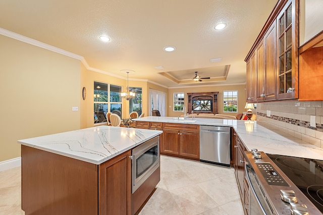 18974 SE Jupiter River Dr, Jupiter, FL 33458 - kitchen with stainless steel appliances, brown cabinets, a sink, ornamental molding, and a peninsula