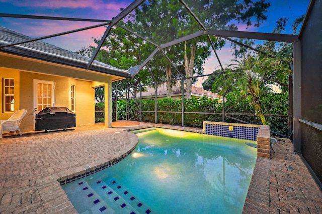 18974 SE Jupiter River Dr, Jupiter, FL 33458 - pool at dusk featuring grilling area, a patio area, a lanai, and an outdoor pool