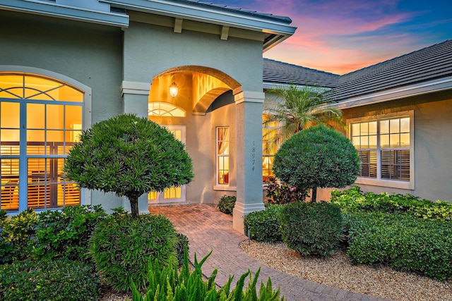 18974 SE Jupiter River Dr, Jupiter, FL 33458 - exterior entry at dusk featuring stucco siding