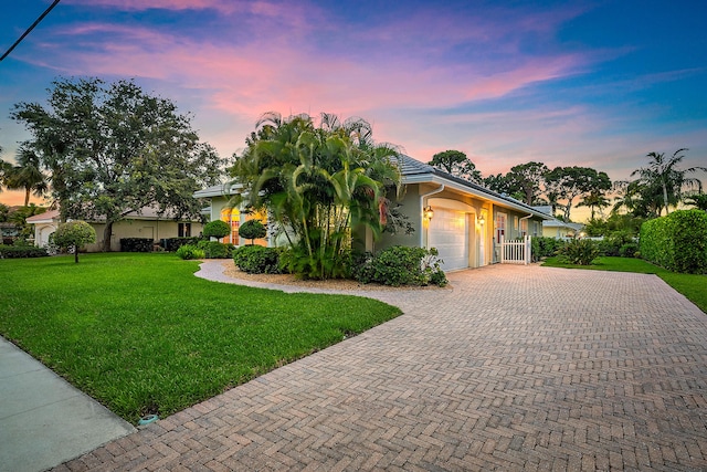 18974 SE Jupiter River Dr, Jupiter, FL 33458 - view of front of property featuring a garage, a lawn, driveway, and stucco siding