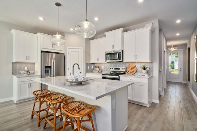 7472 Lenora Ln, Lake Worth, FL 33467 - kitchen with stainless steel appliances, tasteful backsplash, a kitchen island with sink, white cabinetry, and recessed lighting
