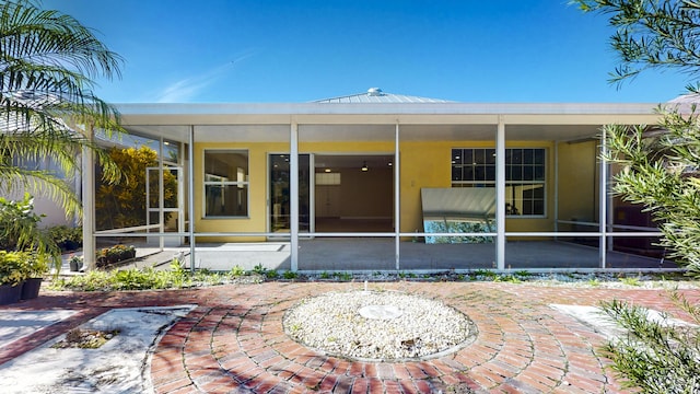 2925 SW Brighton Way, Palm City, FL 34990 - rear view of house featuring a sunroom, stucco siding, and a patio area
