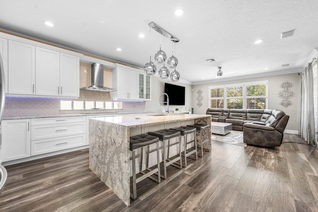 9961 Marsala Way, Delray Beach, FL 33446 - kitchen featuring wall chimney exhaust hood, crown molding, a sink, dark wood-style flooring, and white cabinets