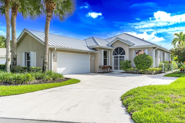 2608 SW Greenwich Way, Palm City, FL 34990 - ranch-style home with a standing seam roof, stucco siding, a metal roof, a garage, and driveway