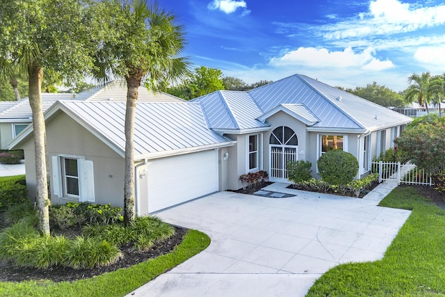 2608 SW Greenwich Way, Palm City, FL 34990 - view of front facade with a standing seam roof, a metal roof, stucco siding, and a garage