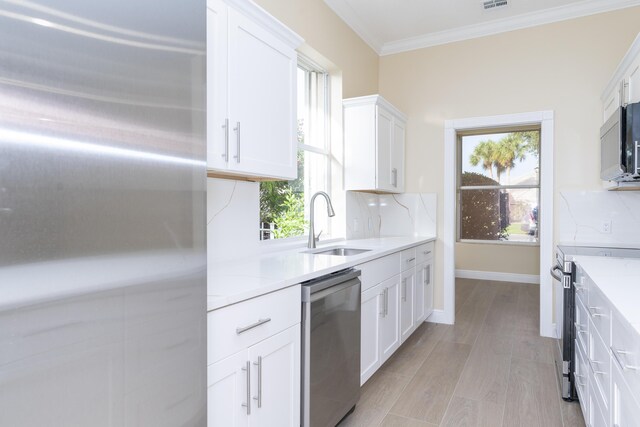 2608 SW Greenwich Way, Palm City, FL 34990 - kitchen with appliances with stainless steel finishes, light countertops, white cabinetry, crown molding, and tasteful backsplash