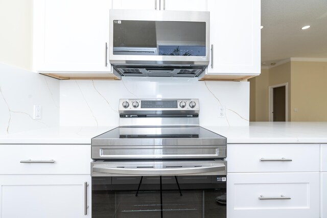 2608 SW Greenwich Way, Palm City, FL 34990 - kitchen with appliances with stainless steel finishes, light countertops, white cabinetry, and ornamental molding
