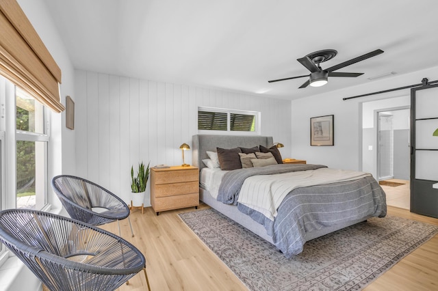 354 Country Club Dr, Tequesta, FL 33469 - bedroom with a barn door, light wood-style floors, and ceiling fan
