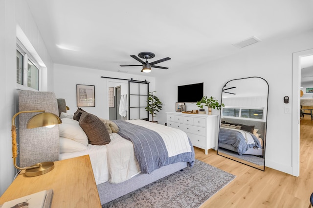 354 Country Club Dr, Tequesta, FL 33469 - bedroom featuring a barn door, light wood-style floors, and ceiling fan