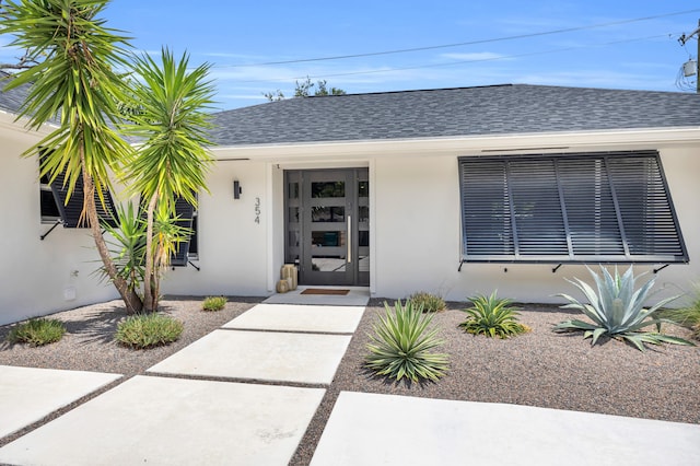354 Country Club Dr, Tequesta, FL 33469 - view of exterior entry with stucco siding and roof with shingles