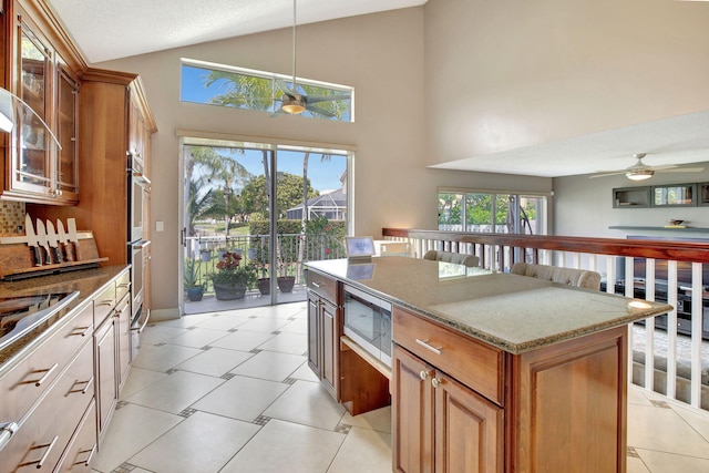 1503 NW 159th Ln, Pembroke Pines, FL 33028 - kitchen featuring ceiling fan, stainless steel appliances, light stone countertops, a kitchen island, and high vaulted ceiling