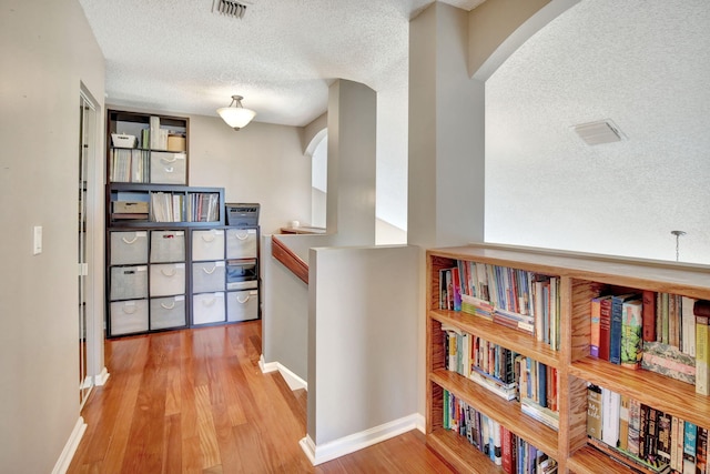 1503 NW 159th Ln, Pembroke Pines, FL 33028 - hallway with arched walkways, a textured ceiling, wood finished floors, an upstairs landing, and baseboards