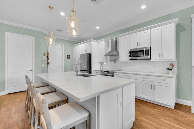 49 Lancaster Rd, Boynton Beach, FL 33426 - kitchen featuring appliances with stainless steel finishes, wall chimney exhaust hood, ornamental molding, an island with sink, and white cabinets
