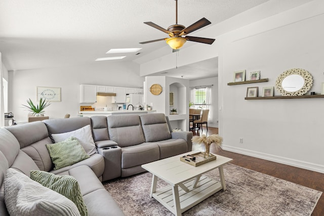 1262 SW Hunnicut Ave, Port Saint Lucie, FL 34953 - living area with ceiling fan, dark wood-type flooring, a skylight, lofted ceiling, and baseboards