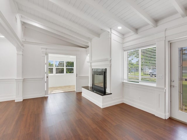 3416 Atlantic Blvd, Vero Beach, FL 32960 - unfurnished living room featuring a multi sided fireplace, a decorative wall, healthy amount of natural light, dark wood-type flooring, and a wainscoted wall