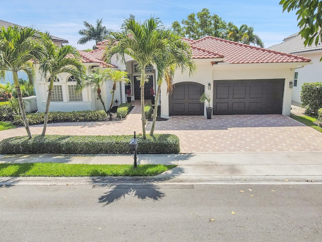 5036 NW 24th Cir, Boca Raton, FL 33431 - mediterranean / spanish-style home with an attached garage, a tiled roof, stucco siding, and decorative driveway