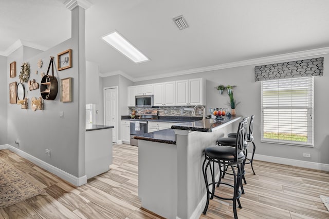 462 SW Sundance Trl, Port Saint Lucie, FL 34953 - kitchen with stainless steel appliances, a kitchen bar, white cabinetry, a peninsula, and ornamental molding