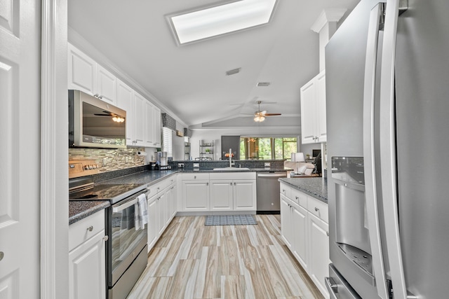 462 SW Sundance Trl, Port Saint Lucie, FL 34953 - kitchen featuring stainless steel appliances, a sink, white cabinets, vaulted ceiling, and a peninsula
