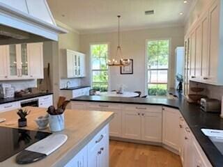 3924 NW 58th St, Boca Raton, FL 33496 - kitchen featuring a peninsula, white cabinets, a chandelier, and crown molding