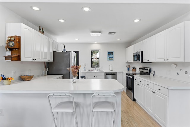 638 NE 8th Ave, Boynton Beach, FL 33435 - kitchen with stainless steel appliances, a peninsula, a sink, a kitchen breakfast bar, and white cabinets