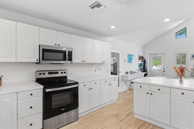 638 NE 8th Ave, Boynton Beach, FL 33435 - kitchen with appliances with stainless steel finishes, lofted ceiling, white cabinets, light wood-type flooring, and light countertops
