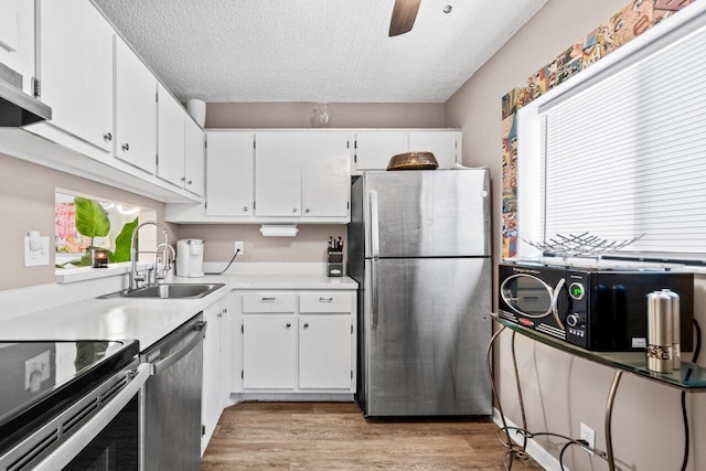 5100 Las Verdes Cir Unit 316, Delray Beach, FL 33484 - kitchen featuring appliances with stainless steel finishes, a sink, light wood-type flooring, white cabinets, and a textured ceiling