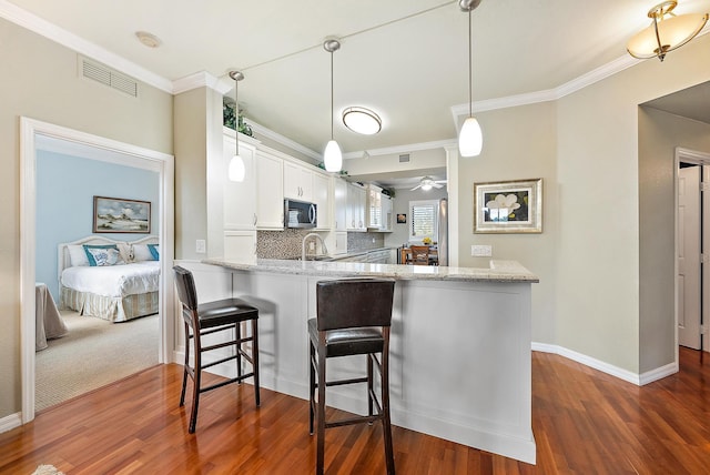 370 Golfview Rd Unit 304, North Palm Beach, FL 33408 - kitchen featuring crown molding, stainless steel microwave, light stone countertops, white cabinetry, and dark wood finished floors