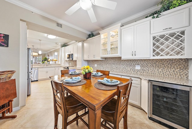 370 Golfview Rd Unit 304, North Palm Beach, FL 33408 - dining area with beverage cooler, light tile patterned flooring, crown molding, a ceiling fan, and a bar
