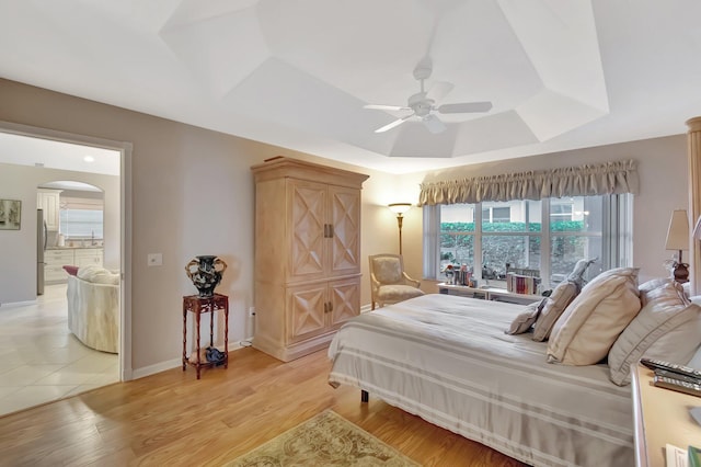 7714 Las Cruces Ct, Boynton Beach, FL 33437 - bedroom featuring a tray ceiling, freestanding refrigerator, arched walkways, light wood-type flooring, and ceiling fan