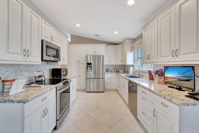 7714 Las Cruces Ct, Boynton Beach, FL 33437 - kitchen with appliances with stainless steel finishes, a sink, decorative backsplash, vaulted ceiling, and white cabinetry