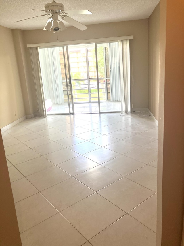 3590 Via Poinciana Unit 303, Lake Worth, FL 33467 - unfurnished room with a textured ceiling, ceiling fan, light tile patterned floors, and baseboards